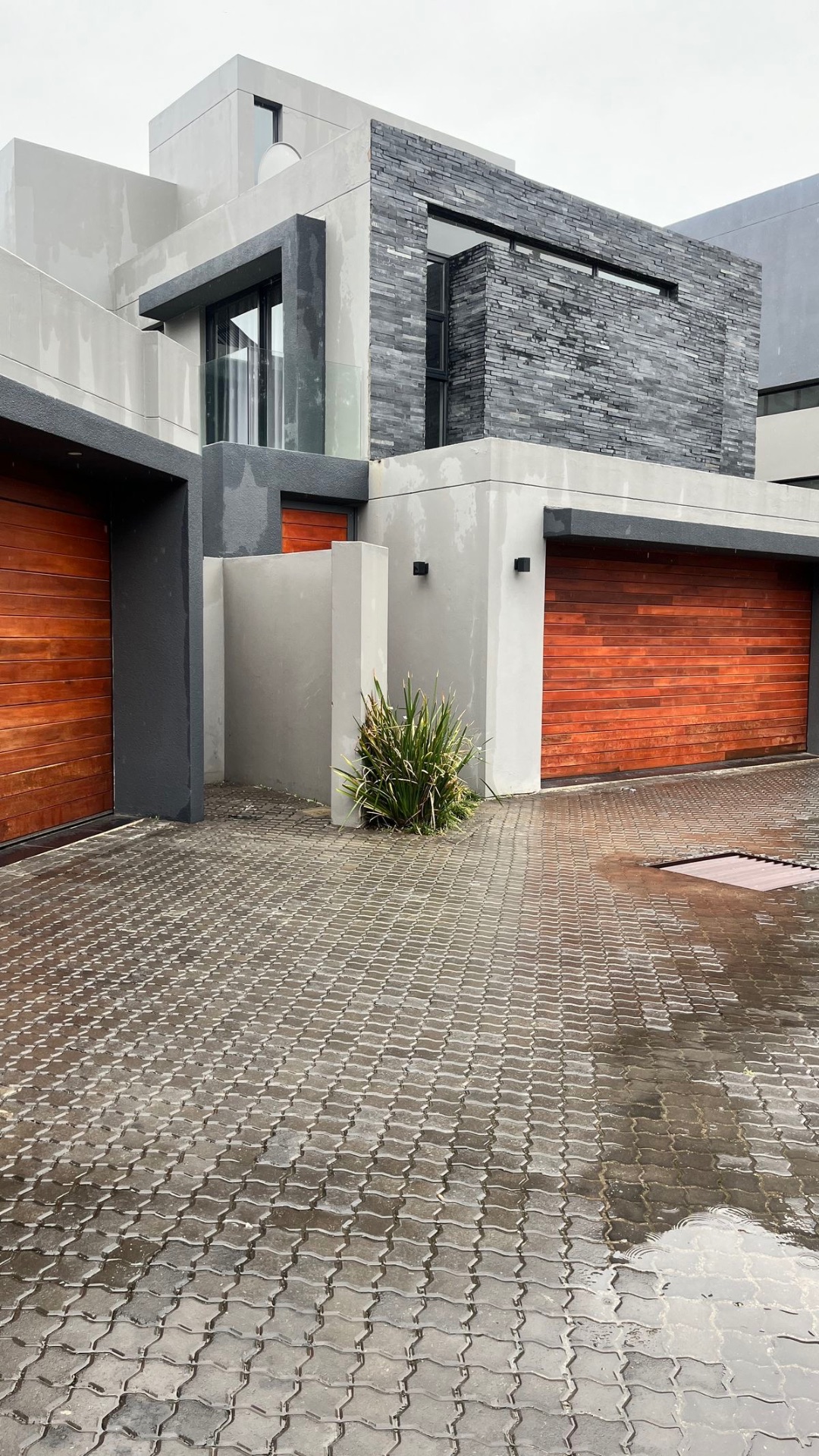 Grey contemporary home with timber garage doors and paved forecourt